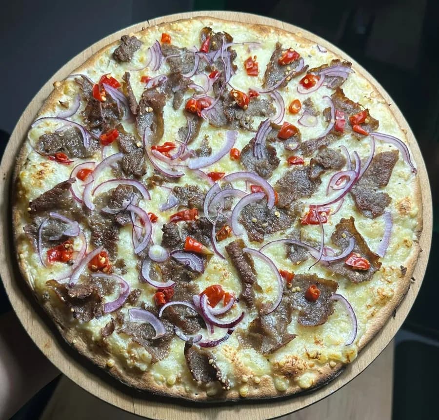 Pizza Z wołowiną: sos biały, mięso wołowe, papryczki piri piri i czerwona cebula